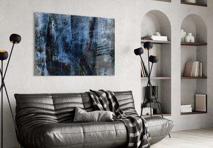 Blue abstract glass wall art with textured layers hung above black leather sofa in modern living room.