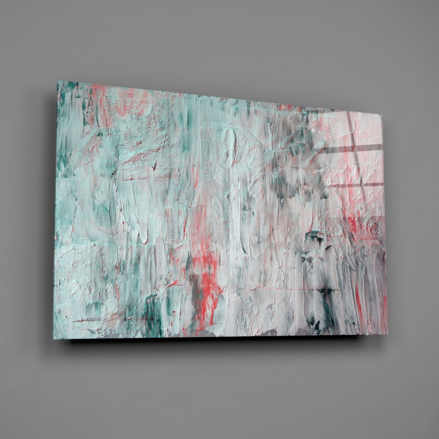 Abstract glass wall art panel with textured oil painting effect in turquoise, coral red, white, and gray brushstrokes, mounted at an angle against gray wall.