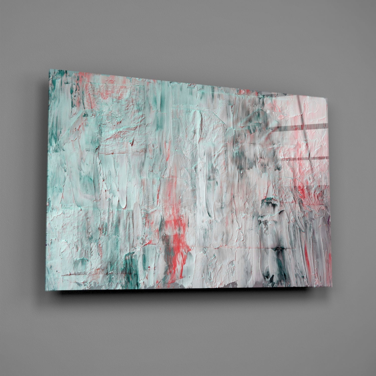 Abstract glass wall art panel with textured oil painting effect in turquoise, coral red, white, and gray brushstrokes, mounted at an angle against gray wall.