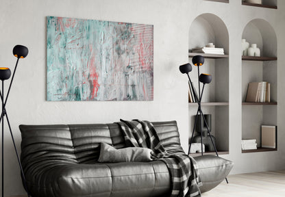 Abstract glass wall art with turquoise, pink, and white textured brushstrokes displayed above a black leather sofa in a modern living room.