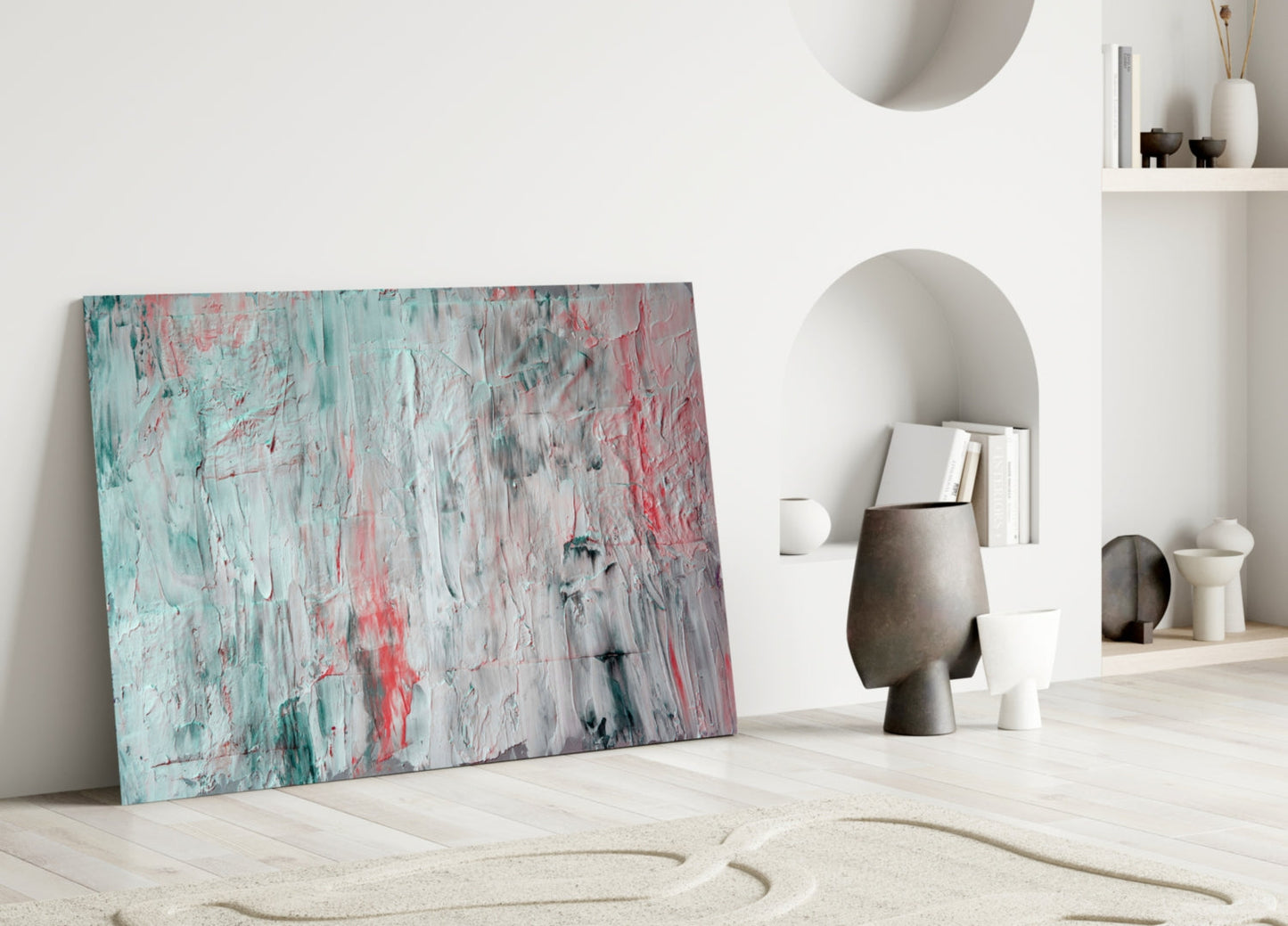 Abstract glass wall art with turquoise, pink, and gray brushstroke pattern leaning against white wall in minimalist interior.