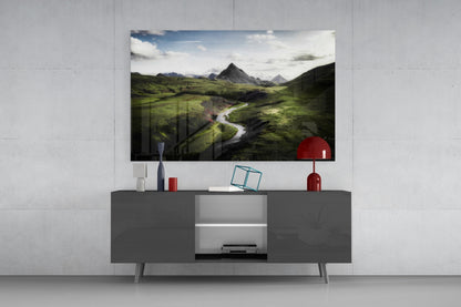 Green Valley Glass Wall Art mounted above a gray media console displaying an Icelandic landscape with mountains, river, and green valleys.