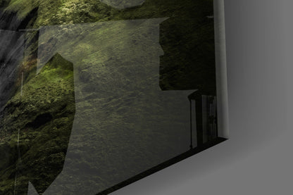 Moss-covered stone wall beside modern white building with black railing detail, angled architectural view.
