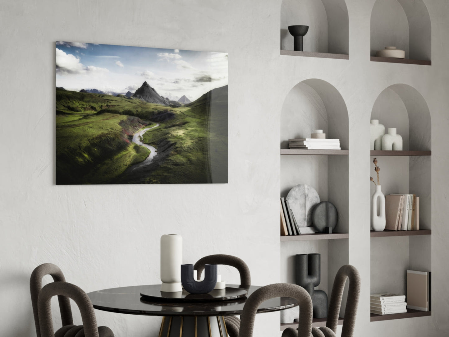 Aerial landscape photograph of green valley with winding river and mountains, displayed as glass wall art in modern dining room setting.