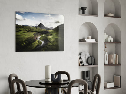 Aerial landscape photograph of green valley with winding river and mountains, displayed as glass wall art in modern dining room setting.