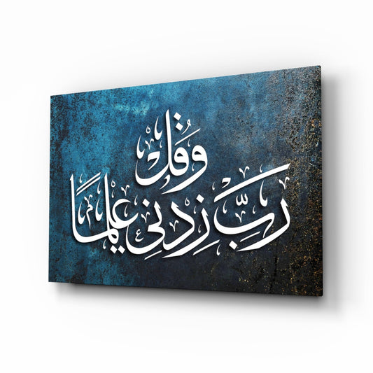 Angled perspective of blue textured glass wall art with white Arabic calligraphy, displaying Rabbi Zidni Ilma text against dark gradient background.