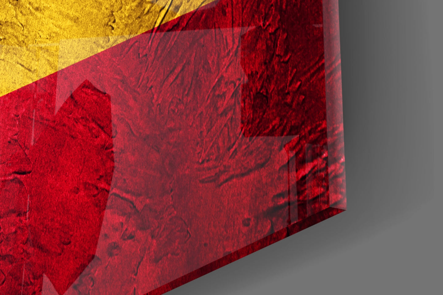 Close-up angled view of red and yellow glass art with textured surface detail against gray background.