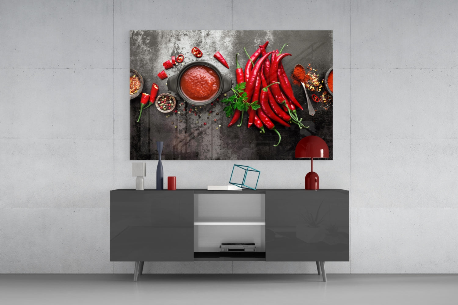 Red Peppers Glass Wall Art displayed above dark TV console in modern living room setting, showing vibrant chili peppers and sauce composition.