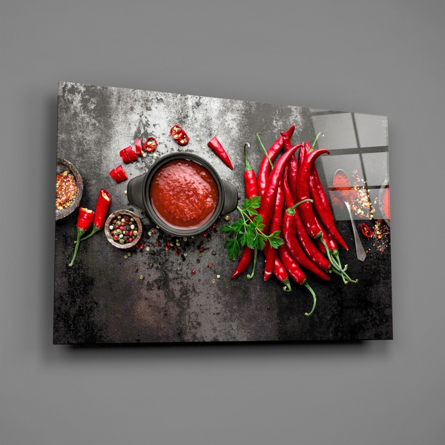 Glass wall art displaying overhead flat lay of red chili peppers, tomato sauce, spices, and herbs on dark textured surface.