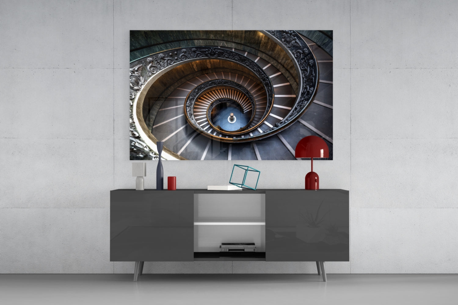 Spiral staircase photograph displayed on wall above dark gray media console with red and white decorative objects.