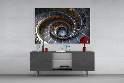 Spiral staircase photograph displayed on wall above dark gray media console with red and white decorative objects.