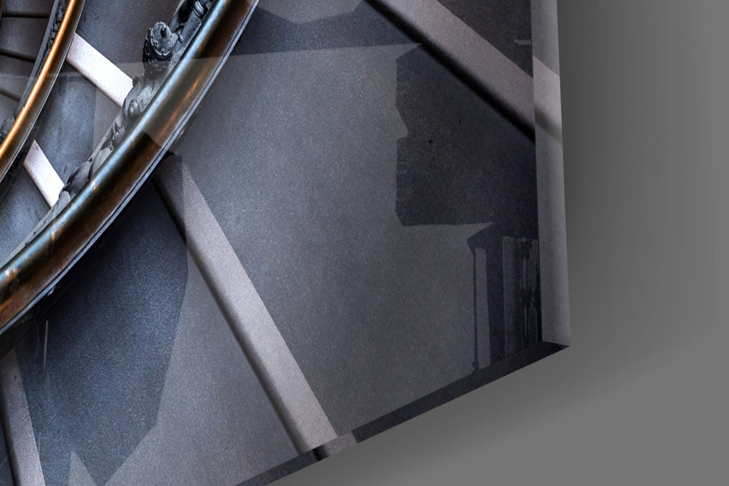 Close-up detail of spiral glass wall art showing layered gray tones, metallic railing, and white mounting hardware against neutral background.
