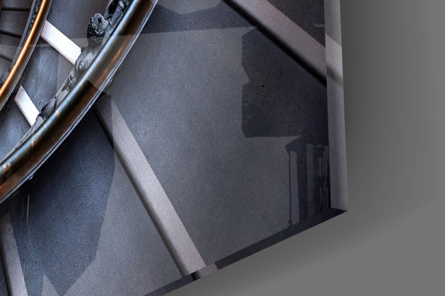 Close-up detail of spiral glass wall art showing layered gray tones, metallic railing, and white mounting hardware against neutral background.
