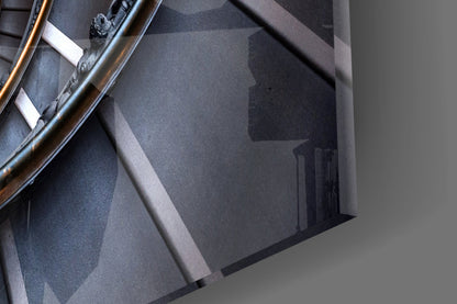 Close-up detail of spiral glass wall art showing layered gray tones, metallic railing, and white mounting hardware against neutral background.