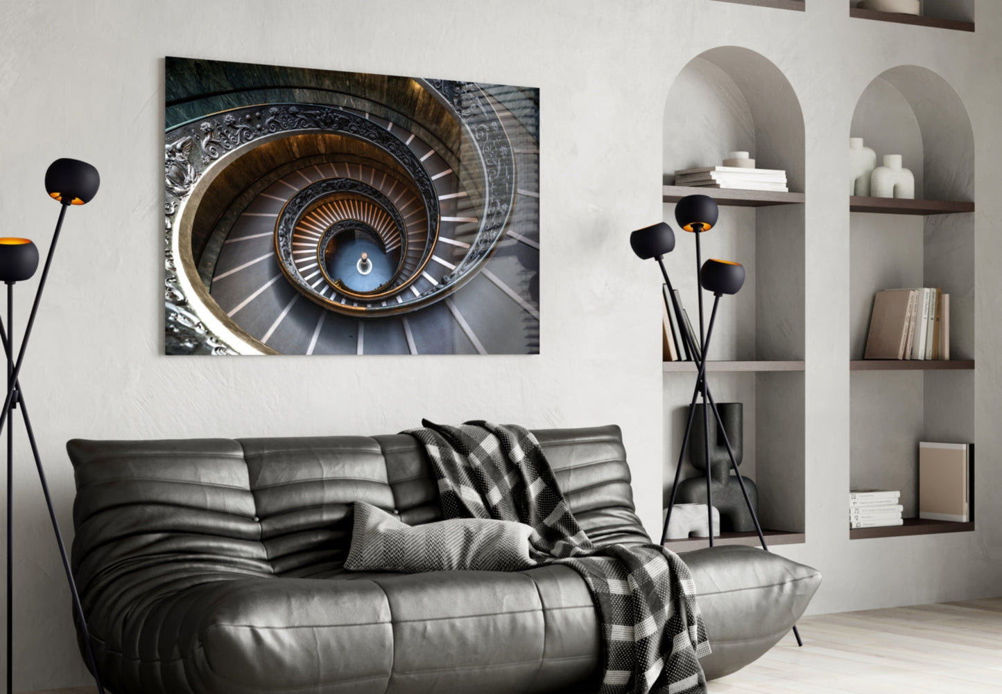 Spiral staircase artwork displayed above black leather sofa in modern living room with white built-in shelving.