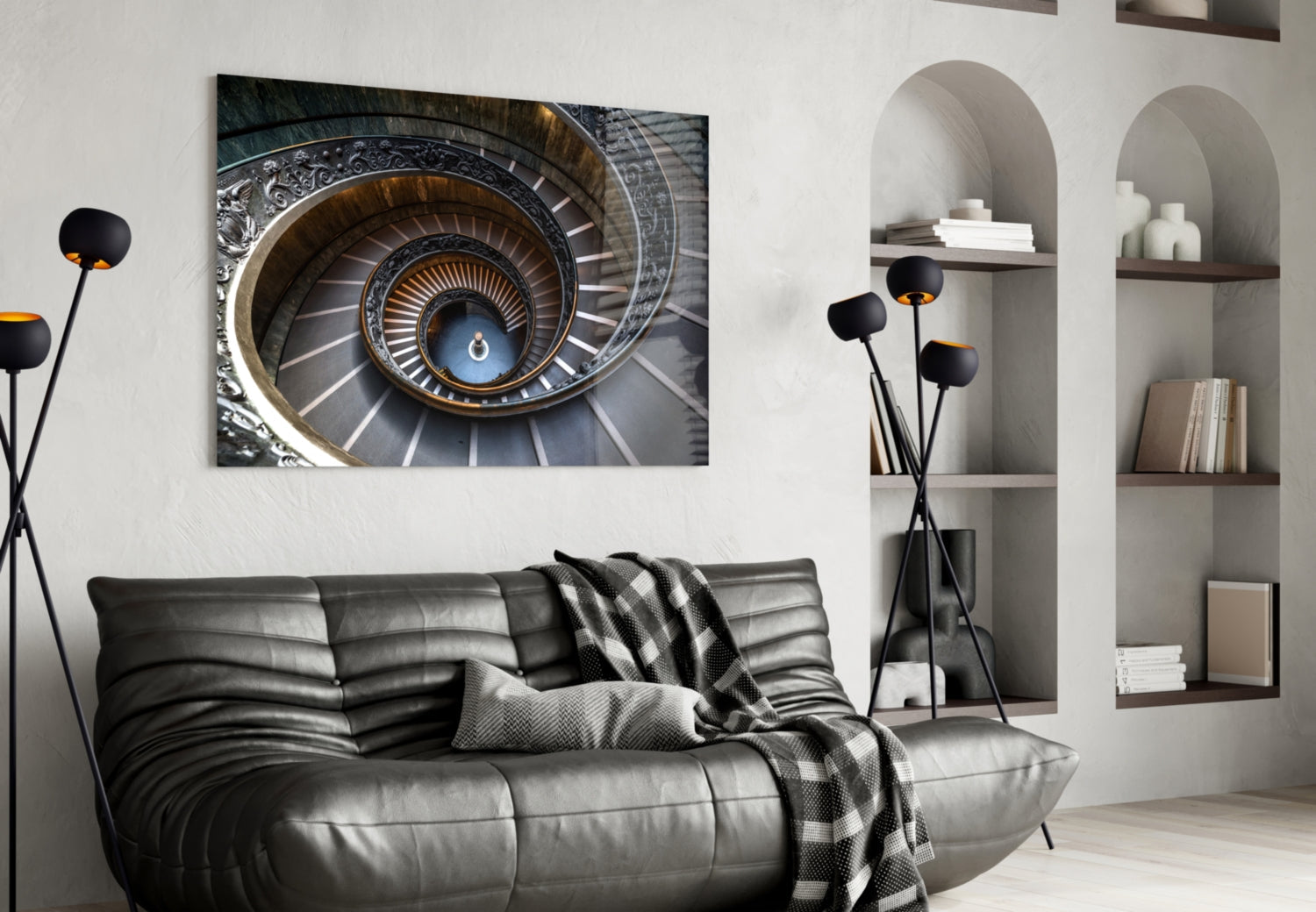 Spiral staircase artwork displayed above black leather sofa in modern living room with white built-in shelving.
