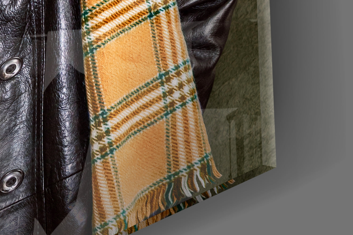 Black leather jacket with metal eyelets next to tartan wool blanket in gold, green, and cream with fringe trim.