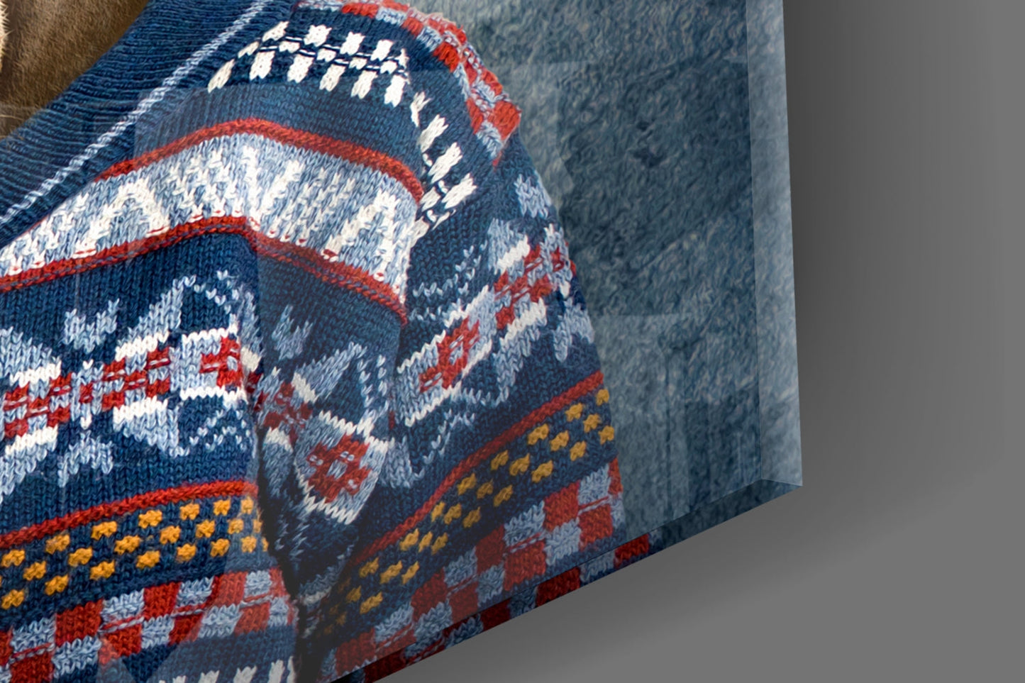 Close-up of knitted sweater with blue, red, white, and gold geometric patterns and deer motif detail.
