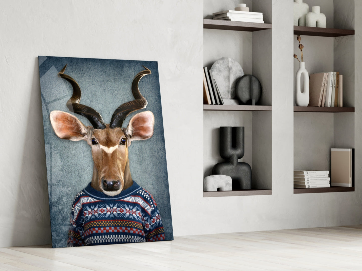 Deer Head Glass Wall Art leaning against white wall beside built-in shelving, displaying antelope in patterned sweater on blue background.