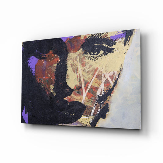 Angled view of a glass wall art panel displaying an abstract face with purple, gold, cream, and dark tones against a light background.