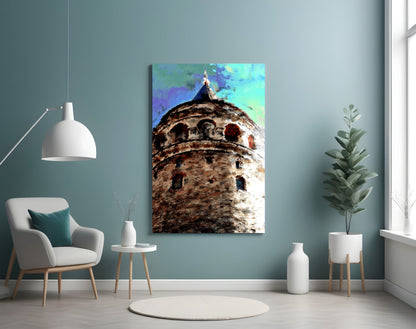 Galata Glass Wall Art displaying a historic stone tower with colorful blue and green sky, mounted on a teal wall above a white chair.
