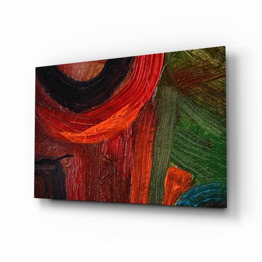 Red, black, orange, and green oil brushstrokes on glass wall art displayed at an angle against white background.
