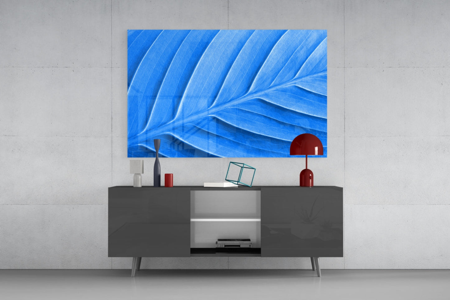 Blue Leaf Glass Wall Art displayed above a dark gray media console with red decorative accessories in a modern living room setting.