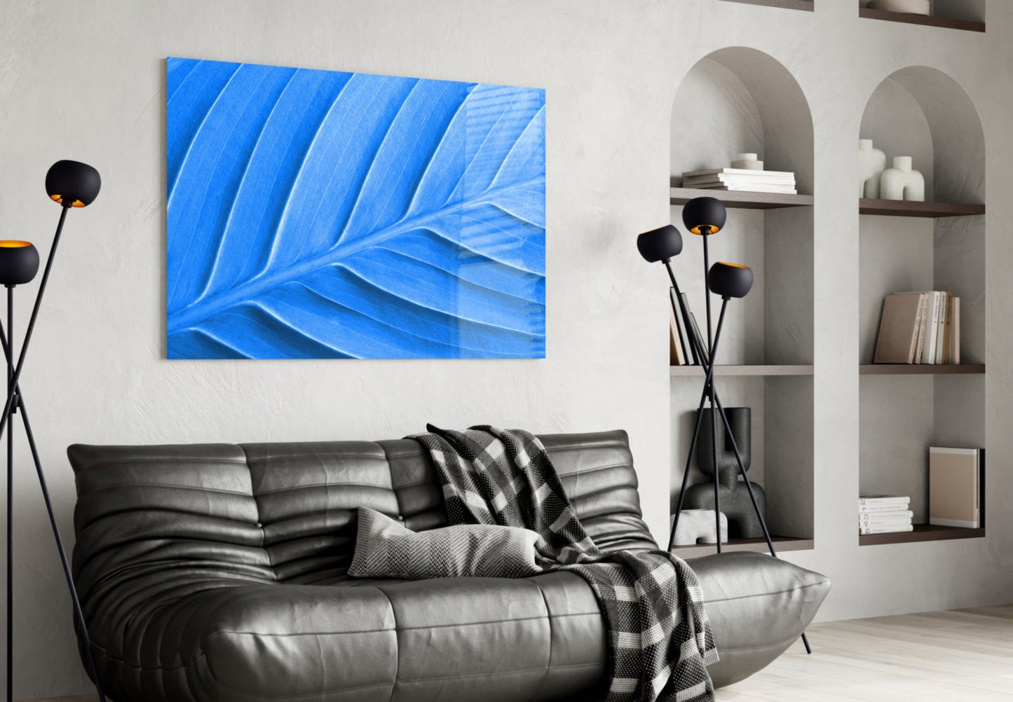 Blue leaf glass wall art hanging above a black leather sofa in a modern living room setting.