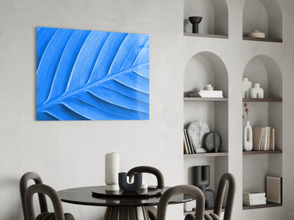 Blue leaf glass wall art displayed above a black round dining table with gray chairs in a modern interior with built-in shelving.