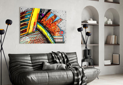 Colorful abstract glass artwork with geometric patterns and bright yellows, reds, and blues displayed above a black leather sofa in a modern living room.