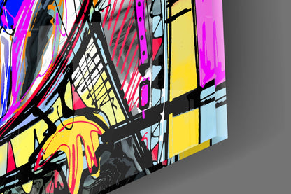 Colorful abstract glass wall art featuring vibrant geometric shapes in magenta, yellow, red, and blue with bold black outlines, photographed at an angled perspective against gray background.