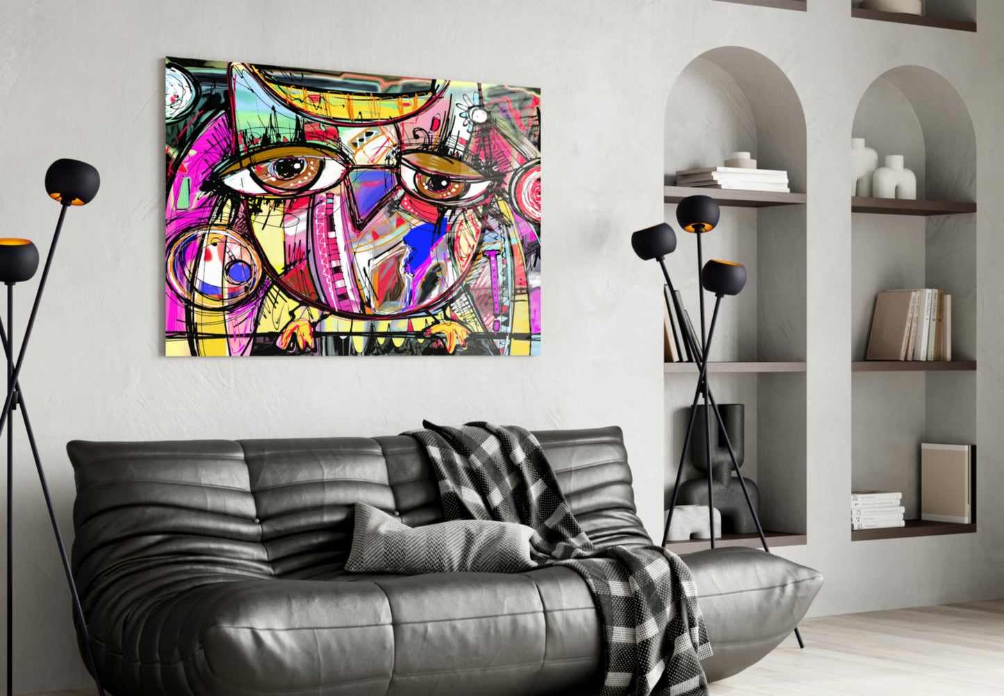 Colorful abstract owl glass wall art with vibrant pink, yellow, and blue geometric patterns displayed above a black leather sofa in a modern living room.