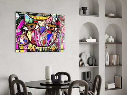 Colorful abstract owl glass wall art with magenta, yellow, and blue patterns displayed above a dining table in a modern interior.