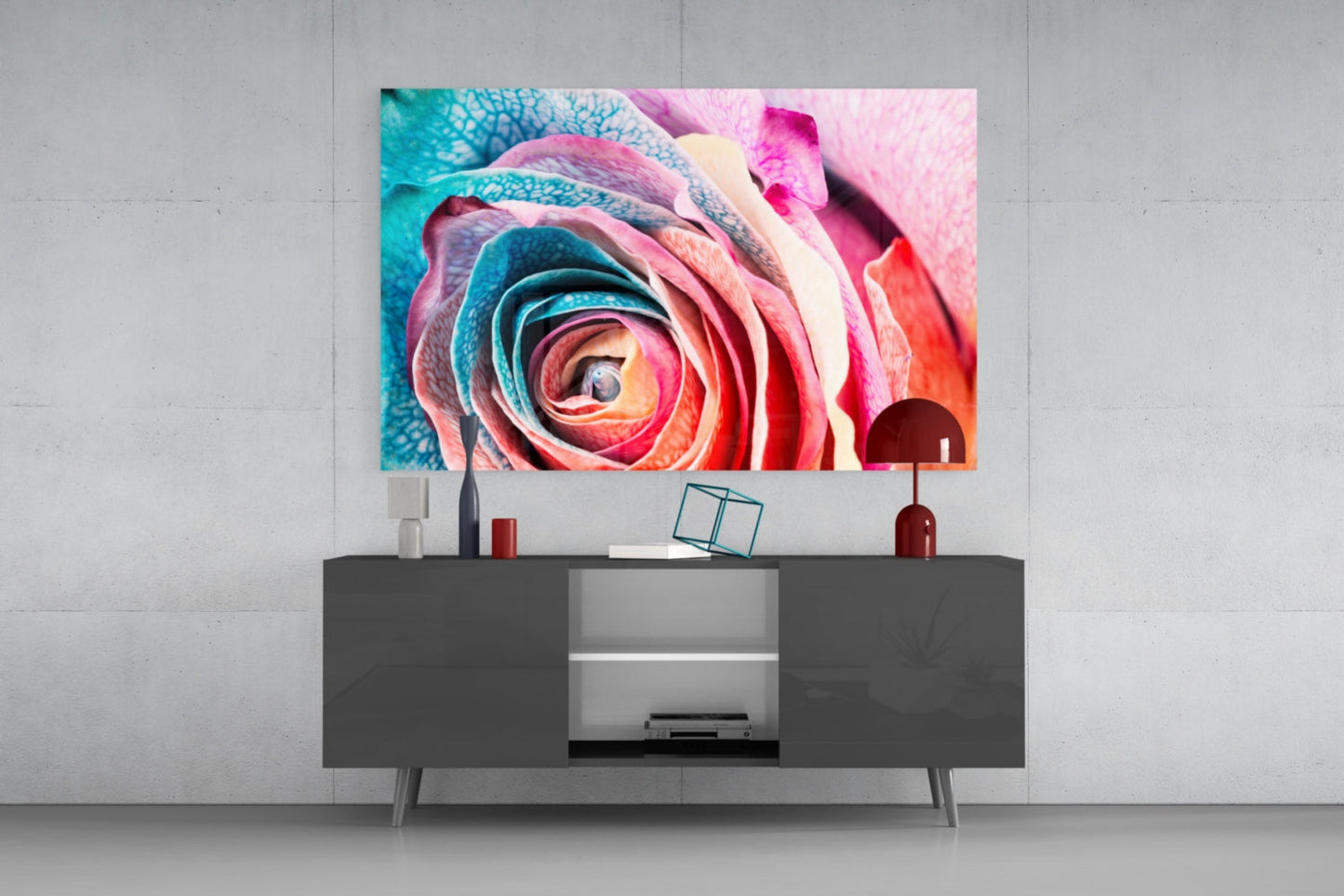 Colorful rose glass wall art displaying pink, red, and turquoise petals mounted above a dark gray media console in a modern interior setting.