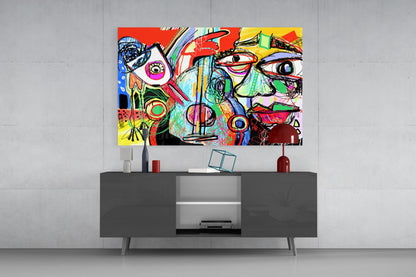 Colorful abstract glass wall art featuring vibrant red, yellow, blue, and green geometric designs with stylized faces displayed above a dark gray media console.