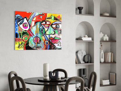 Colorful abstract glass wall art depicting a stylized face with bird and violin elements in vibrant reds, yellows, blues, and greens, displayed above a black dining table in a modern interior.