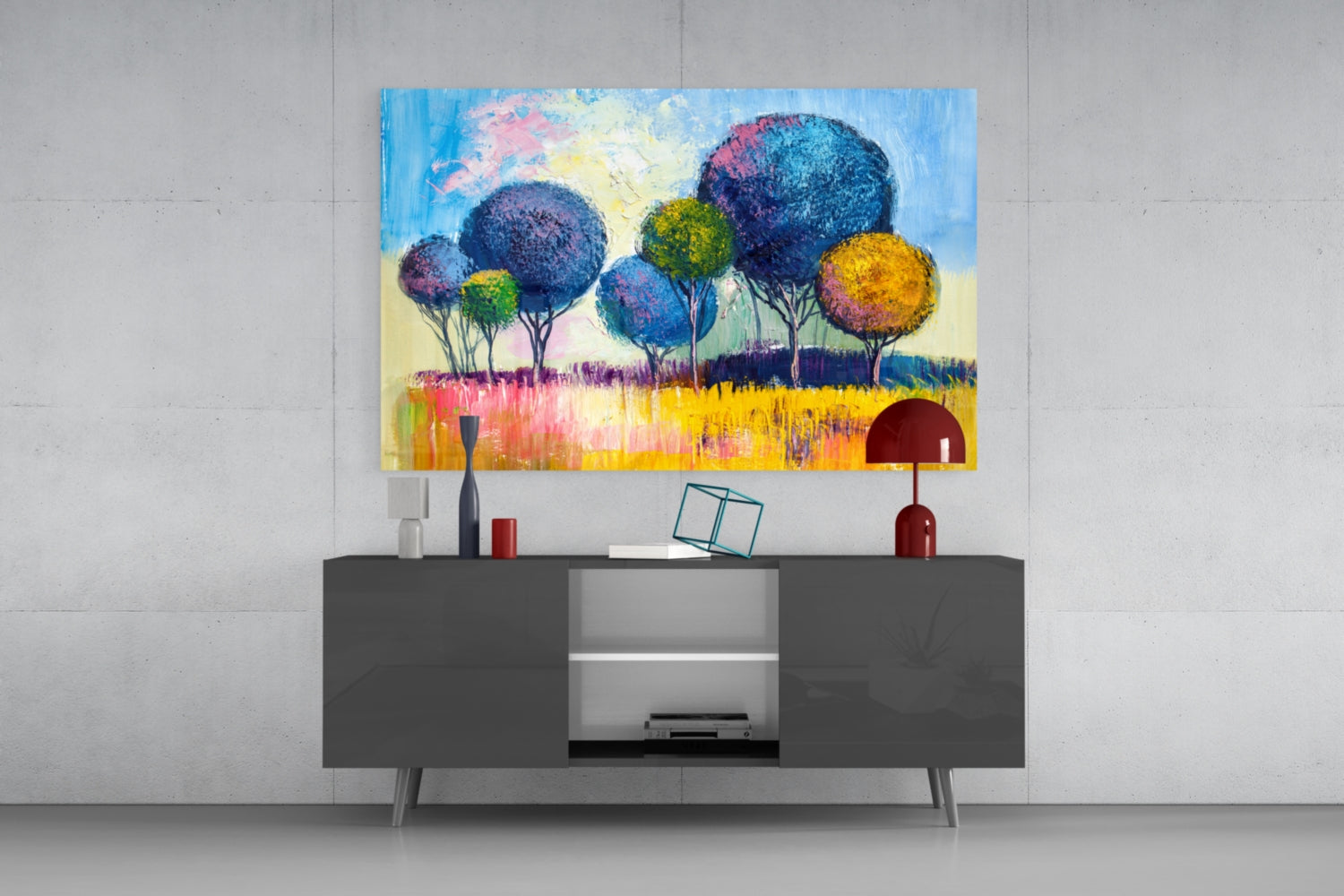 Colorful glass wall art featuring blue, yellow, and pink trees in a landscape, displayed above a dark grey console table in a modern interior.