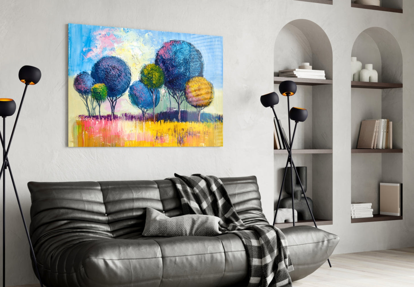 Colorful glass wall art depicting vibrant blue, yellow, and pink trees displayed above a black leather sofa in a modern living room interior.