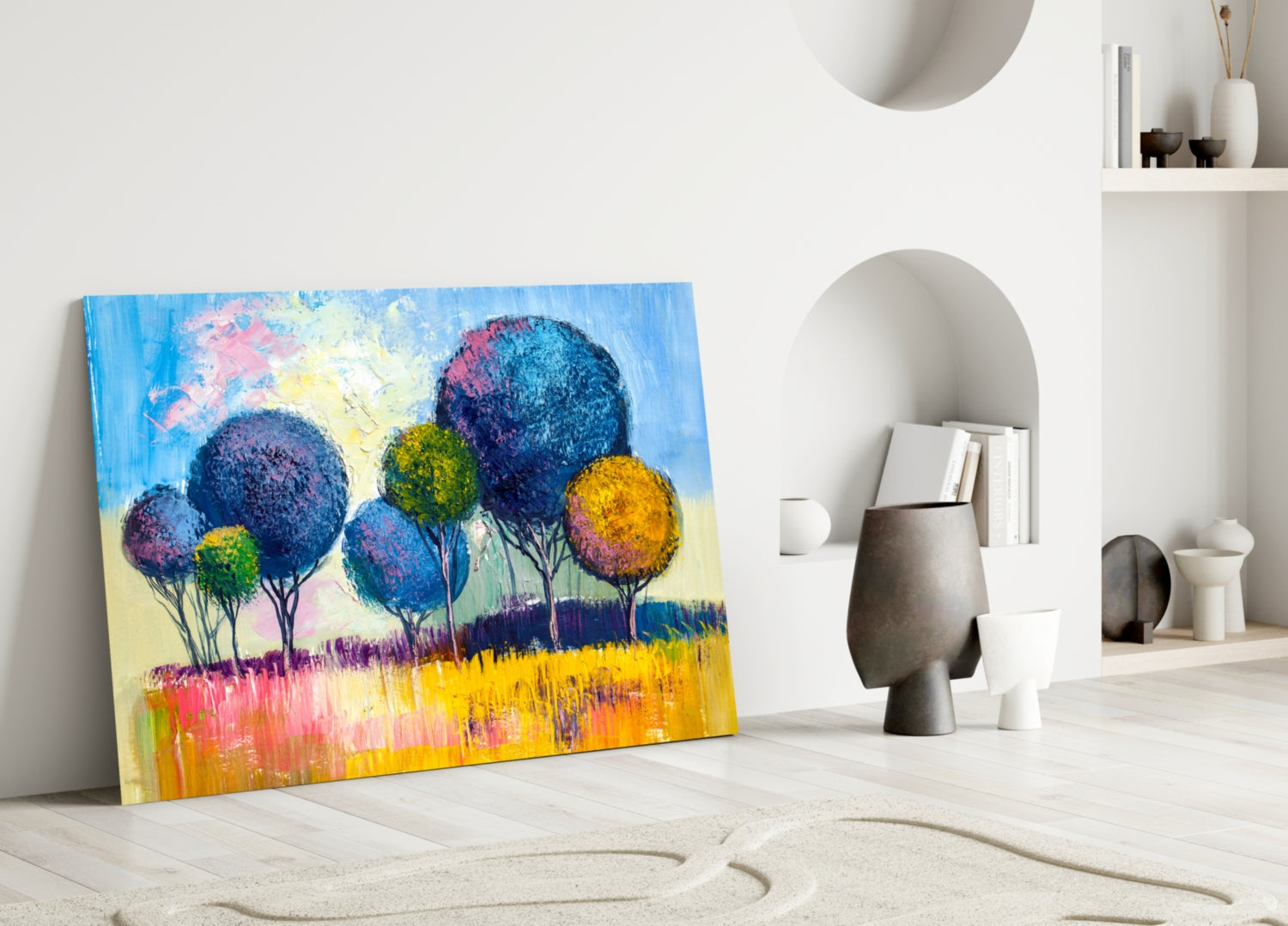 Colorful glass wall art leaning against white wall displays vibrant blue, pink, yellow trees in landscape scene.