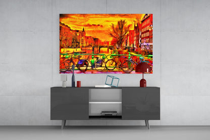 Colorful glass wall art depicting vibrant bicycles and orange sunset cityscape displayed above dark modern TV console in contemporary living room.