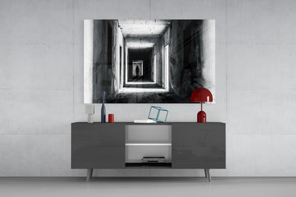 Black and white photograph of a receding corridor with a silhouetted figure, displayed above a dark gray media console with red accents.