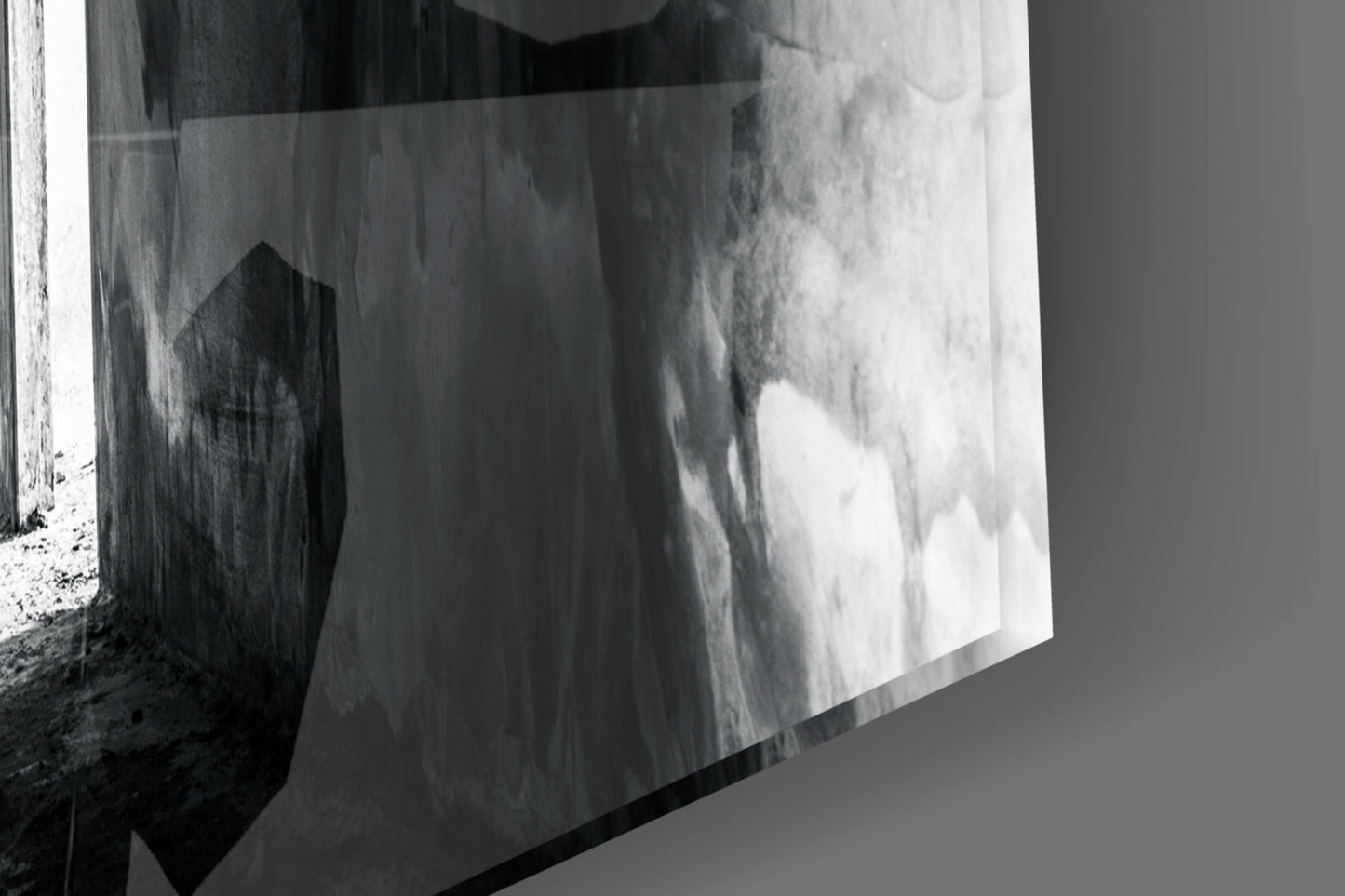 Black and white photograph of a textured concrete wall with dramatic light and shadow effects creating an abstract composition.
