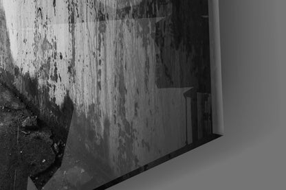 Black and white photograph of a weathered concrete wall with peeling paint, displayed as glass wall art mounted on white surface.