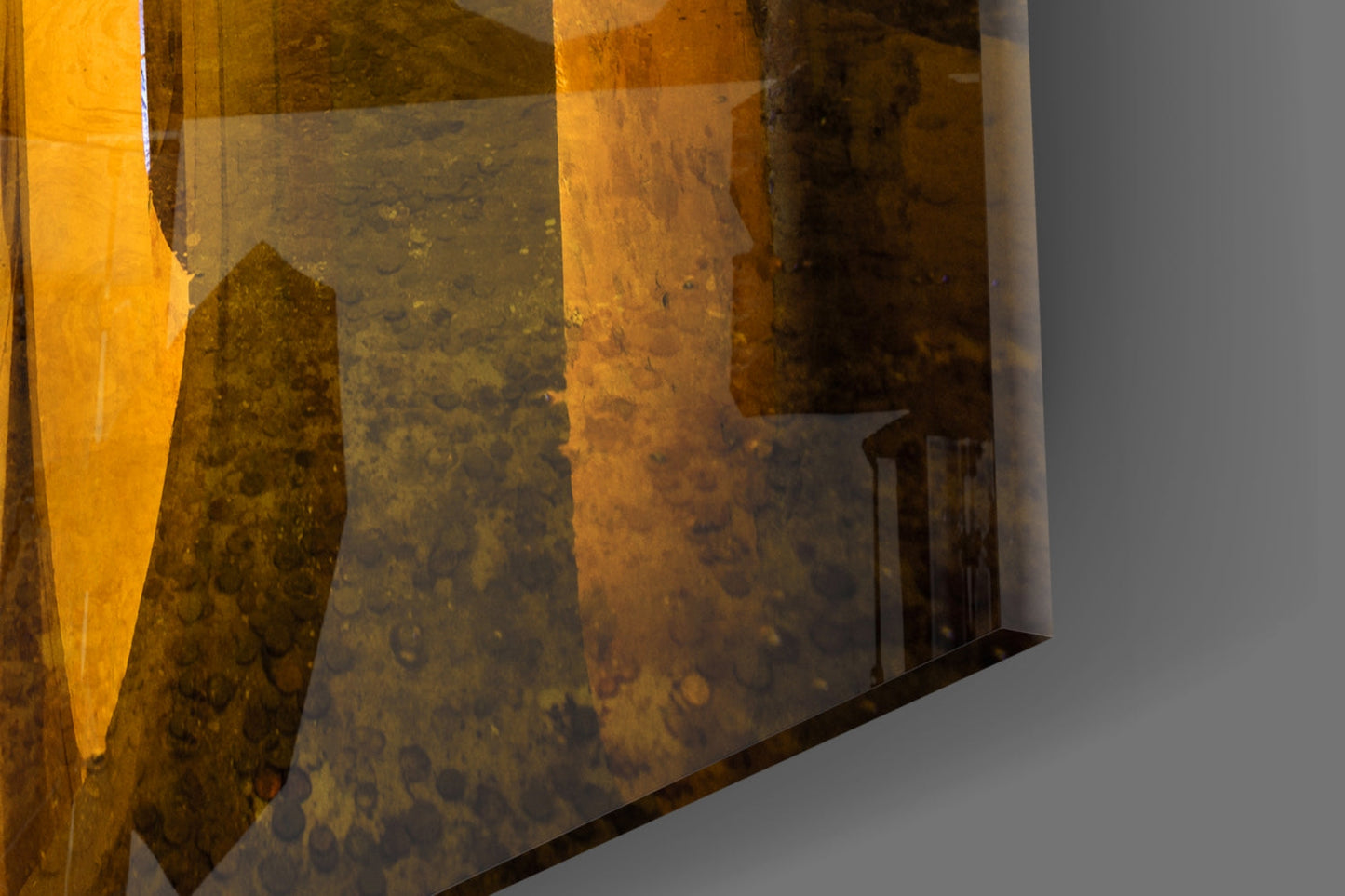 Close-up detail of amber and brown translucent glass panels with textured surface patterns and layered edges against gray background.