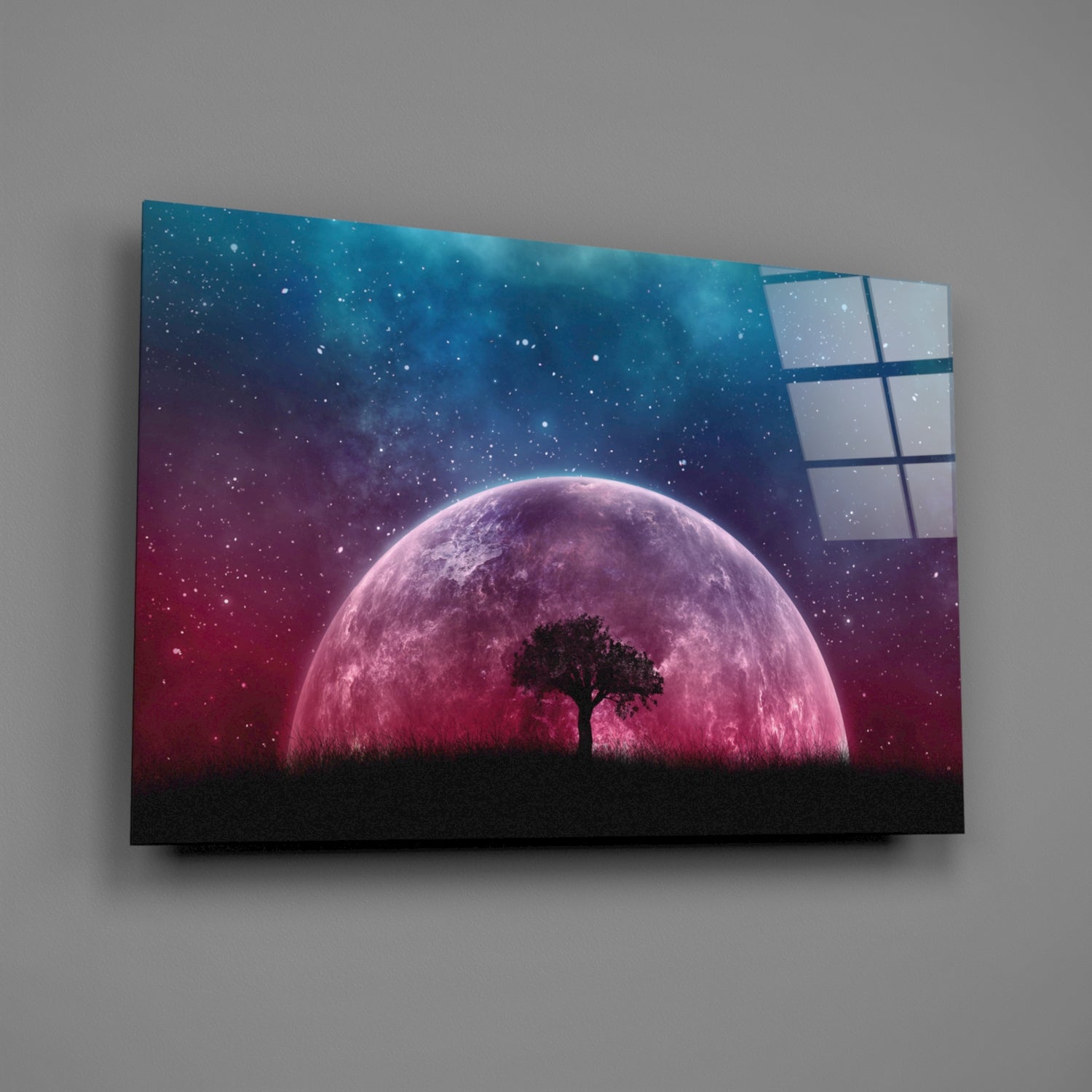 Glass wall art featuring silhouetted tree against large pink moon with starry blue-to-red gradient sky, displayed at angle.