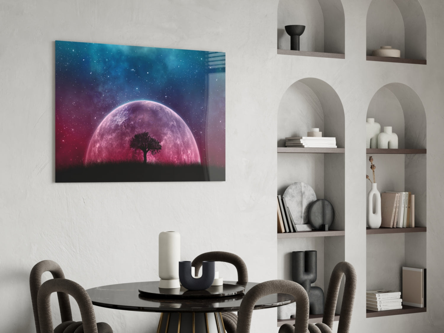 Glass wall art depicting a pink glowing moon with silhouetted tree against starry blue and purple sky, displayed above round black dining table.