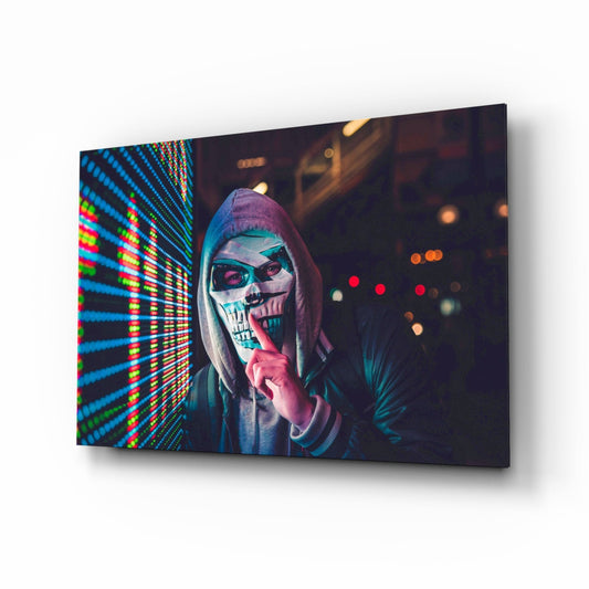 Angled view of glass wall art displaying a hooded figure with skull face paint against colorful neon lights.