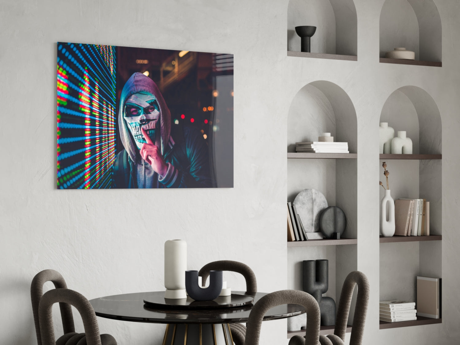 Neon skull artwork displayed on white wall above black round dining table with gray chairs and white shelving unit.