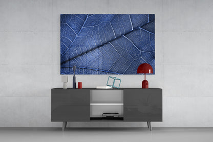 Blue leaf-vein glass artwork displayed above a dark gray media console with red decorative accessories in a modern living room setting.