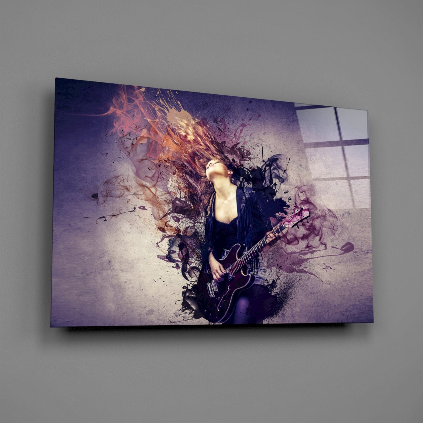 Glass wall art mounted on gray wall displaying female guitarist with flowing hair and colorful paint splash effects in purple and orange tones.